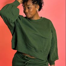 Load image into Gallery viewer, Black girl smiling wearing green joggers in front of pink background.
