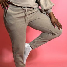 Load image into Gallery viewer, black girl standing and wearing oatmeal colored joggers in front of a pink background.
