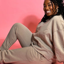 Load image into Gallery viewer, black girl smiling and wearing oatmeal colored joggers in front of a pink background.
