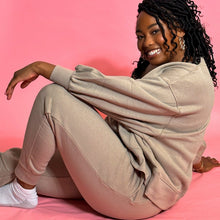 Load image into Gallery viewer, black girl smiling and wearing oatmeal colored joggers in front of a pink background.
